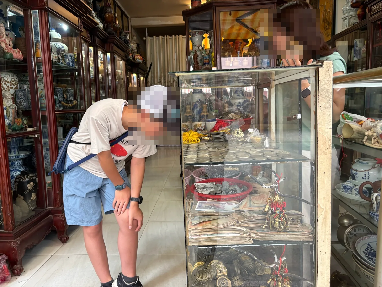 レ・コン・キエウ通りの骨董店で店員と古銭を見ている子ども